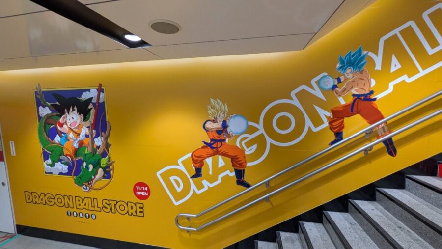 Interior de la tienda teñido de naranja y amarillo, con murales de la saga Dragon Ball desde sus inicios hasta Ultra Instinct | Imagen: Dragon Ball Store Tokyo